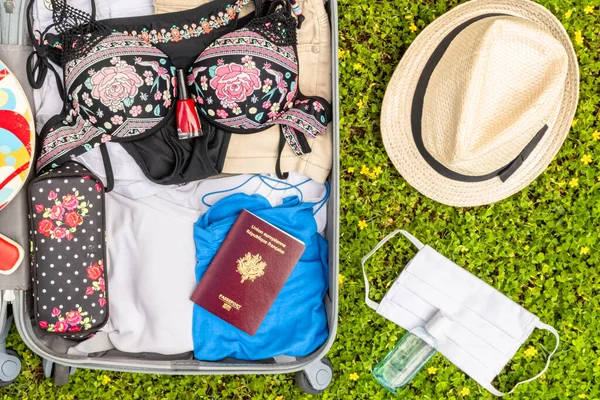 Tekerlekli bavul, yüz koruması için maske ve covid-19 virüsü, koronavirüs, alerji, salgın hastalık ve pandemiye karşı savaşmak için hidroalkolik jelle gezilere çıkıyor..