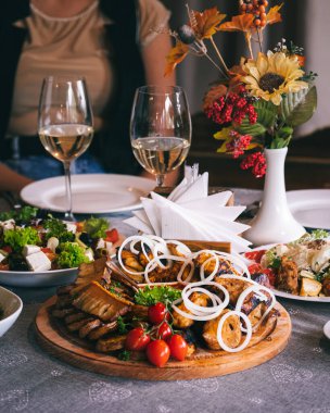 Barbekü, sos ve salata tabağı. Restoranda akşam yemeği. Arka planda beyaz şarap kadehleri var..