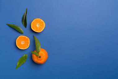 Renkli arka planda taze mandalinalarla yatıyordu. Üst görünüm.