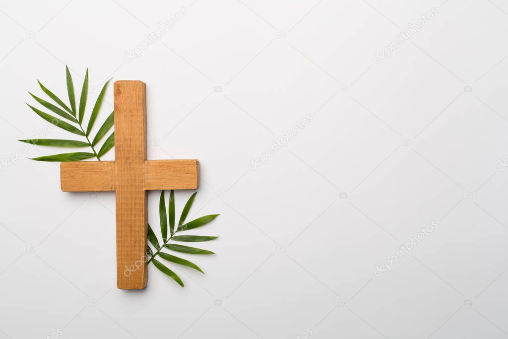 Palm branches and cross on white background, top view. Palm Sunday concept.