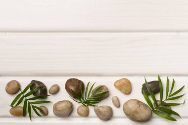 Tahta arka planda kaplıca taşları ve yapraklar, üst manzara.