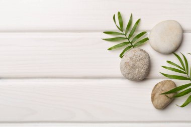 Tahta arka planda kaplıca taşları ve yapraklar, üst manzara.