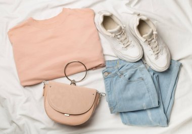 Beyaz çarşafın üzerinde kadın kıyafetleriyle yatıyordu.,