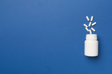 Arka planda haplar olan beyaz şişe..