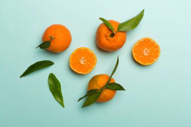 Renkli arka planda taze mandalinalarla yatıyordu. Üst görünüm.