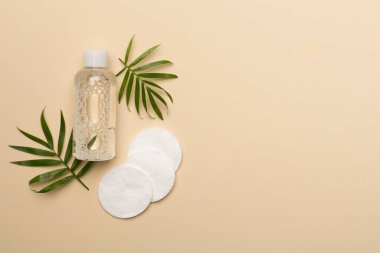 Renk arkaplanına Micellar temizleme suyu ve pamuk pedleri, üst görünüm.