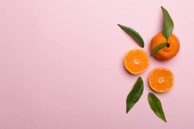 Renkli arka planda taze mandalinalarla yatıyordu. Üst görünüm.