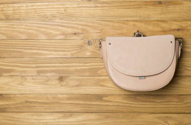 Ahşap arka planda şık bir kadın çantası. Üst görünüm.