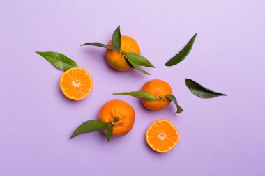 Renkli arka planda taze mandalinalarla yatıyordu. Üst görünüm.