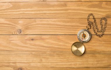 Old vintage compass on wooden background. Top view. clipart