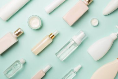 Renkli arka planda farklı kozmetik şişeleri, üst görünüm.