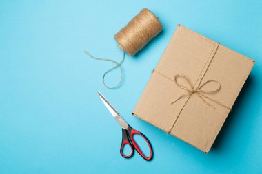 Renk arkaplanında kutu, ip ve makas.