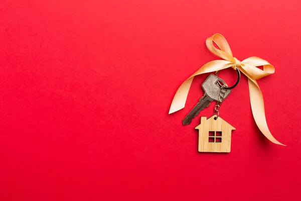 House key with golden bow on color background.