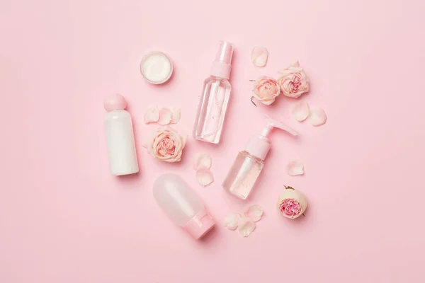 Set of small cosmetic bottles on color background, top view.