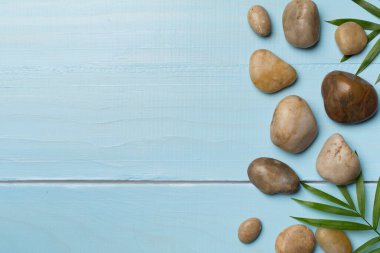 Tahta arka planda kaplıca taşları ve yapraklar, üst manzara.