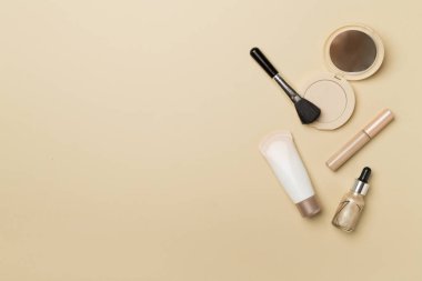 Makeup products for skin tone on color background, top view.