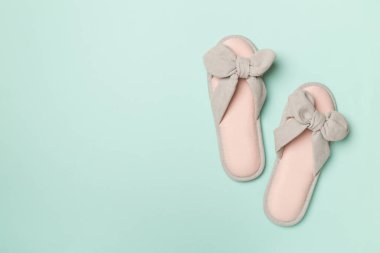 Soft pink slippers on color background, top view.