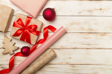 Gift boxes, paper's rools and decorations on wooden background, top view.