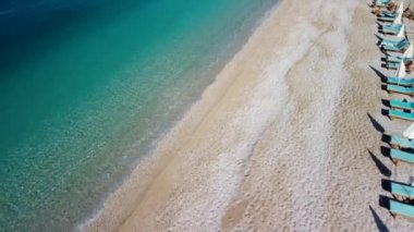Dynamic fly over the Oludeniz beach in Fethiye with sun loungers and turquoise sea.