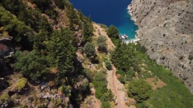 Fethiye 'deki Kelebek Vadisi' nin güzelliği, dağ yamaçlarının arkasındaki video, turkuaz su ve sahildeki turistik tekneler..