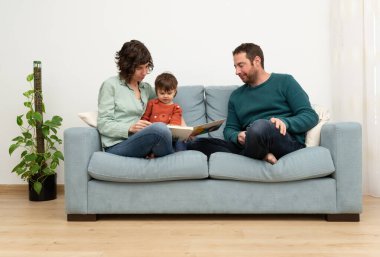 Aile (anne, baba ve çocuk) sof üzerine bir kitap okuyor. Birlikte zaman geçirmek. 