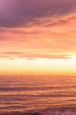 Denizin üzerinde mor ve turuncu gün batımı. 