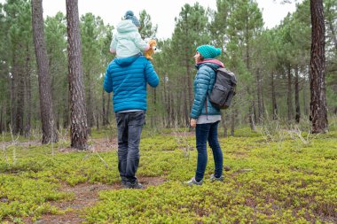 Küçük kızlarıyla birlikte bir kış gününü ormanda geçiren genç bir çift. Aile yürüyüşü. Aktif sağlıklı yaşam tarzı. 