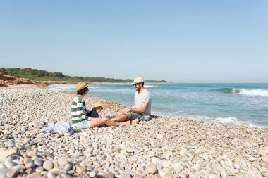 Tek çocuklu bir aile kumsalda güzel bir gün geçiriyor. Akdeniz kıyısında dinlendirici ve huzurlu tatiller. 