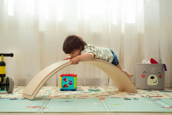 Little girl playing with a balance board as if it were a slide.