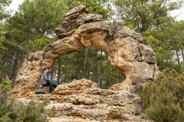Man resting alone on a natural rock arch.  Lifestyle adventure vacations. 