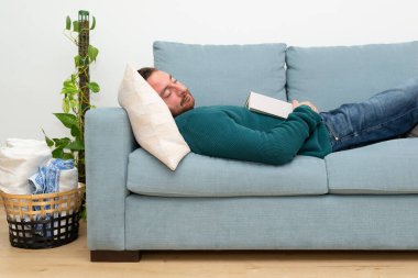 Young man fall asleep while reading a novel. Weekend mood. 