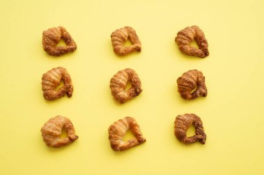 Homemade croissants on vibrant yellow background. Flat lay.