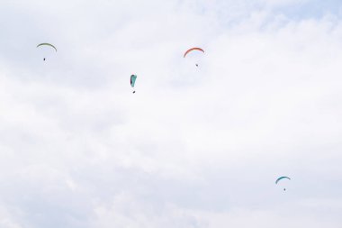 Bulutlu bir günde uçan bir paraglider grubu.
