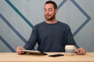 Yakışıklı bir işadamının portresi, günlük kıyafetlerini dijital tablette okuyor.. 