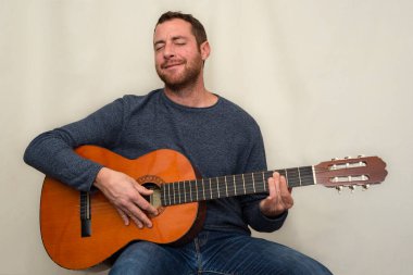 Çekici bir adam gitar çalıyor ve müziği hissediyor.. 