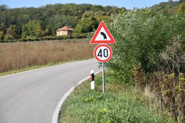 Saatte maksimum 40 kilometre hız gösteren yol işaretleri ve önümüzdeki yolda sürücüleri keskin virajda uyaran imzalar.