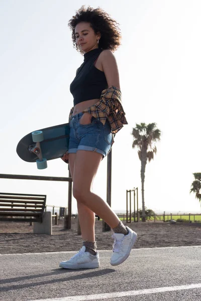 Νεαρή Γυναίκα Σκέιτερ Μαλλιά Afro Περπάτημα Εξωτερικούς Χώρους Κρατώντας Skateboard — Φωτογραφία Αρχείου