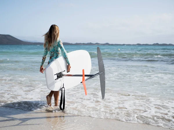 뒤에서 바다로 걸어가던 여자가 하이드로 서핑을 연습하고 있습니다 — 스톡 사진