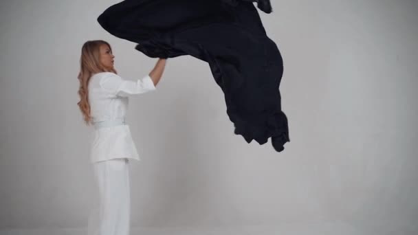 Mulher em um fundo branco acenando lenço preto. Movimento lento — Vídeo de Stock
