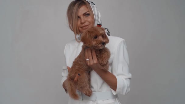 Chica de moda con bufanda sosteniendo un perro caniche en sus brazos. Movimiento lento — Vídeos de Stock