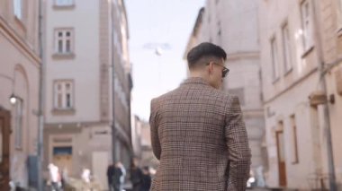 Paltolu bir adam caddede yürüyor. Adam gözlüklerini çıkarıyor. Şehir merkezinde yürü. Yavaş çekim