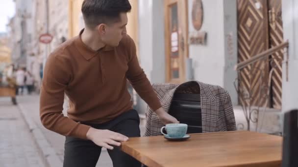 Homme dans un café se lève de sa chaise et ramasse son manteau. Mouvement lent — Video