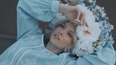 Kafasında çelenk olan Ukrayna vatandaşı bir kadın. Nakış. Nakış. Sahilde yatan kadın