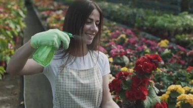 Kız bahçede çiçek sıkıyor. Kafkasyalı kadın bitkileri nemlendirerek ilgilenir. Bahçeciliğin yavaş çekim videosu