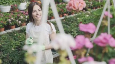 Kız bahçede çiçek sıkıyor. Kafkasyalı kadın bitkileri nemlendirerek ilgilenir. Bahçeciliğin yavaş çekim videosu