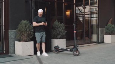 Tourist man on electric scooter with phone in hand. New sharing business project started in city, eco transportation