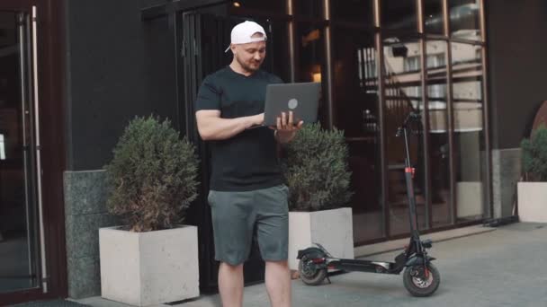 在城市的大街上 穿着电动车的成年人正在用笔记本电脑工作 一个年轻人骑电动车 — 图库视频影像