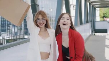 Happy young girls friends with shoping bags, talking and laughing. slow mo steadicam shot