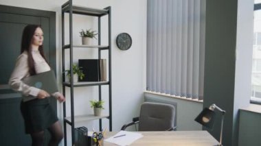 Ofisinde dizüstü bilgisayarı olan uzun saçlı bir iş kadını. Ciddi kadın dizüstü bilgisayarı masaya koyar ve gülümser. İş içeriği