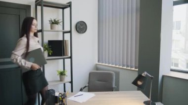 Ofisinde dizüstü bilgisayarı olan uzun saçlı bir iş kadını. Ciddi bayan dizüstü bilgisayarı masaya koyar. İş içeriği